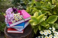 stack of multi-colored several books lie in the garden on a stump among flowers Royalty Free Stock Photo