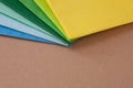 a stack of multi colored tissue paper spread out in a fan on a background of brown cardboard Royalty Free Stock Photo
