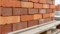 Stack of multi-toned red and orange bricks on a wooden pallet ready for construction Royalty Free Stock Photo