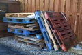 Stack of multicolored wood forklift pallets near dumpster Royalty Free Stock Photo