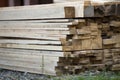 Stack of natural brown uneven rough wooden boards on building site. Industrial timber for carpentry, building, repairing and