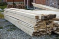 Stack of natural brown uneven rough wooden boards on building site. Industrial timber for carpentry, building, repairing and