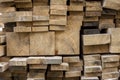 Stack of natural brown uneven rough wooden boards different size, cross-sectional view. Industrial timber for carpentry, building,