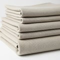 A stack of neatly folded beige fabric pieces rests on a white surface. The material Royalty Free Stock Photo