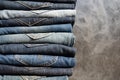 A stack of neatly folded jeans on gray background. Close-up of jeans in different colors. Denim background. Copy space Royalty Free Stock Photo