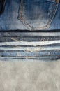 A stack of neatly folded jeans on gray background. Close-up of jeans in different colors. Copy space. Selective focus Royalty Free Stock Photo
