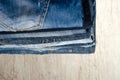 A stack of neatly folded jeans on wooden background. Close-up of jeans in different colors. Jeans background. Copy space Royalty Free Stock Photo
