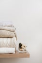 A stack of neatly folded warm knitwear, wool on a wooden shelf and a beige background. Royalty Free Stock Photo