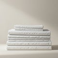A stack of neatly folded white fabric, possibly bed linens, placed against a neutral Royalty Free Stock Photo