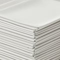 A stack of neatly folded, white fabric sheets creates a uniform pattern. The material Royalty Free Stock Photo