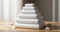 A stack of neatly folded, white towels arranged in a pyramid shape is on a wooden Royalty Free Stock Photo