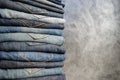 A stack of neatly folded woman`s jeans on gray background. Close-up of jeans in different colors. Copy space Royalty Free Stock Photo