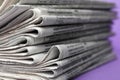 Stack of newspapers on light violet background. Journalist`s work Royalty Free Stock Photo