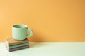 Stack of notebook and mug cup on mint green desk. orange background. copy space Royalty Free Stock Photo