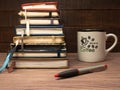 A stack of notebooks and a cup of coffee on a wooden table