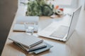 A stack of notebooks and notepads in the foreground. In the background is a laptop and a glass of water. Royalty Free Stock Photo