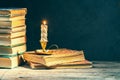 Stack of old antique books and lighten candle Royalty Free Stock Photo