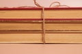 A stack of old battered books tied with a jute rope on a colored background