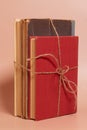 A stack of old battered books tied with a jute rope on a colored background