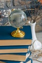 Stack of old books, branches in vase, glass globe, grunge brick Royalty Free Stock Photo