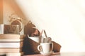 Stack old books with a cup of freshly coffee, vintage alarm clock, wooden calendar, on table in sunlight morning Royalty Free Stock Photo