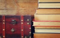 Stack of old books next to antique wooden chest on wooden shelf. vintage filtered