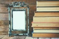 Stack of old books next to vintage blank frame wooden table. vintage filtered image Royalty Free Stock Photo