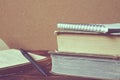 Stack of old books, notebook, opened book with pen on wooden tab