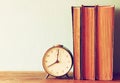 Stack of old books and old clock over wooden table . filtered image Royalty Free Stock Photo