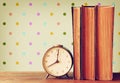 Stack of old books and old clock over wooden table and retro style wallpaper Royalty Free Stock Photo