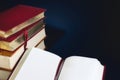 Stack of old books and an open book with blank empty pages against a dark blue background Royalty Free Stock Photo