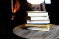 Stack of old books on round wood table with reading light during night Royalty Free Stock Photo