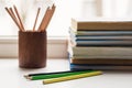 A stack of old books and several different colored pencils lie on the windowsill, a couple of pencils lie ahead Royalty Free Stock Photo