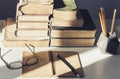 Stack of old books, textbook, glasses and pencils in office background for education retro concept