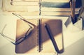 Stack of old books, textbook, notebook, glasses and pencils on white table in office background for education retro concept