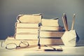 Stack of old books, textbook, notebook, glasses and pencils on white table in office background for education retro concept Royalty Free Stock Photo
