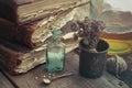 Stack of old books, vintage mortar of medicinal herbs, vial of h