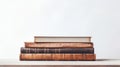 A stack of old books on a wooden surface with a white wall. The books are hardcover with leather covers. The books are