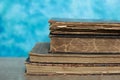 Stack of old books on a wooden table with blue wall background. Royalty Free Stock Photo