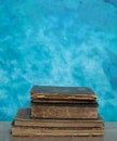 Stack of old books on a wooden table with blue wall background. Royalty Free Stock Photo