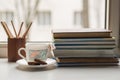 A stack of old different books and several colored pencils lie on the windowsill, a couple of pieces of chocolate, a Cup of milk Royalty Free Stock Photo