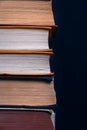 Stack of old dusty hardback books on a dark background.