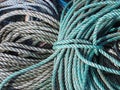 Stack of old green and grey coiled and knotted marine fishing rope