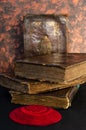 A stack of old leather-bound Jewish books with gold stamping and red knitted jewish bale on black background
