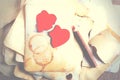 Stack old papers, notebook, wooden pencil and two vintage red hearts on burlap, sackcloth background. Retro design Royalty Free Stock Photo