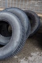 Stack of old used tires of different sizes and types in abandoned scrap yard.