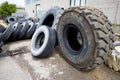 Stack of old used tires of different sizes and types in abandoned scrap yard.