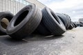 Stack of old used tires of different sizes and types in abandoned scrap yard.