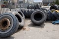 Stack of old used tires of different sizes and types in abandoned scrap yard.