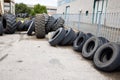 Stack of old used tires of different sizes and types in abandoned scrap yard.